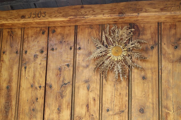 Una flor seca colgada en una pared de madera.