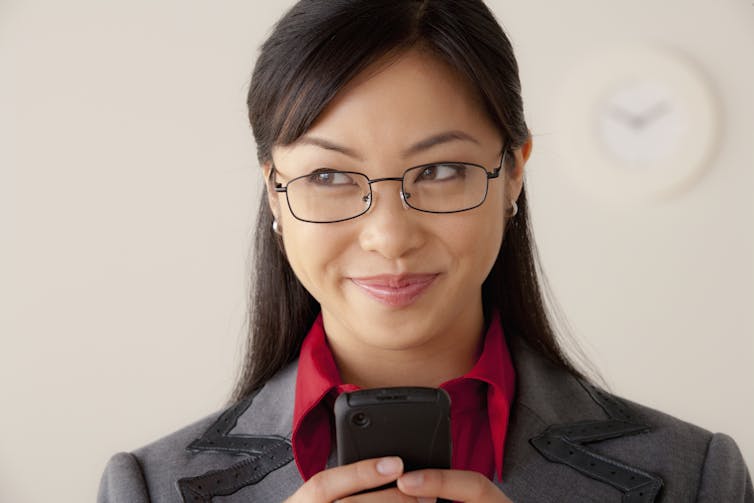 woman with smirking look holding a cellphone