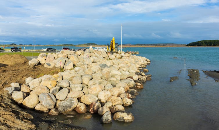 A digger is working on a seawall.