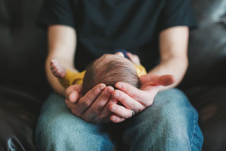 Man holding baby in in arms