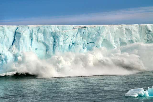 A mass of ice breaking away from an ice sheet and collapsing into the sea.