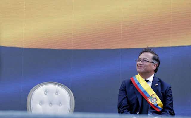 Gustavo Petro sentado con una banda con la bandera de Colombia.