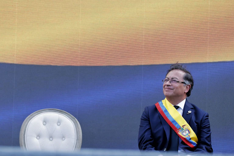 Gustavo Petro sentado con una banda con la bandera de Colombia.