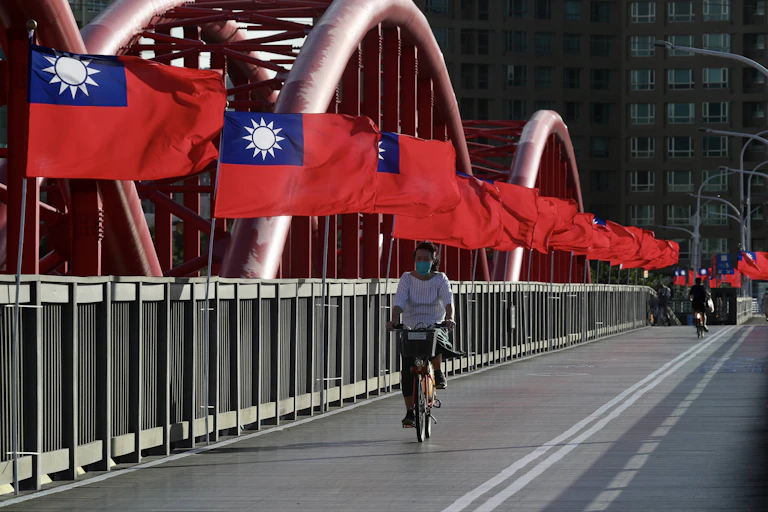 Un ciclista pasa junto a las banderas nacionales de Taiwán en un puente de Taipei.
