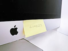 A yellow sticky note with a password is stuck to a computer monitor.