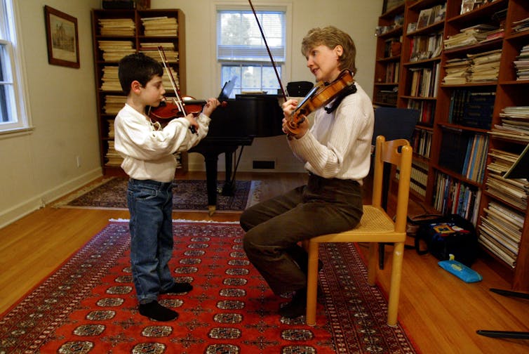 Violin teacher teaching young student