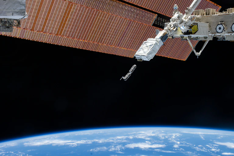 Two small boxes leaving a larger satellite orbiting Earth.