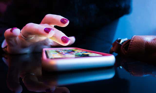 Person with sparkly nail polish using their smartphone in closeup