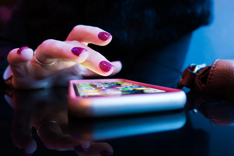 Person with sparkly nail polish using their smartphone in closeup