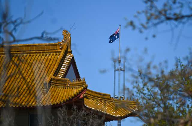 The flag pole of the Australian Parliament is seen behind the roof of the Chinese Embassy in Canberra