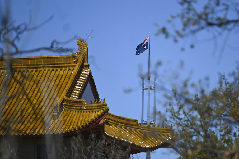 The flag pole of the Australian Parliament is seen behind the roof of the Chinese Embassy in Canberra
