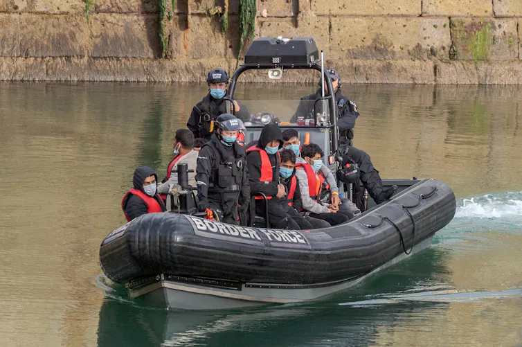 A small Border Force boat carrying a group of young men in red life jackets