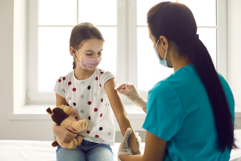 A nurse prepares to give a girl a vaccination.