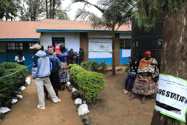 People standing in a short queue in front of a building.