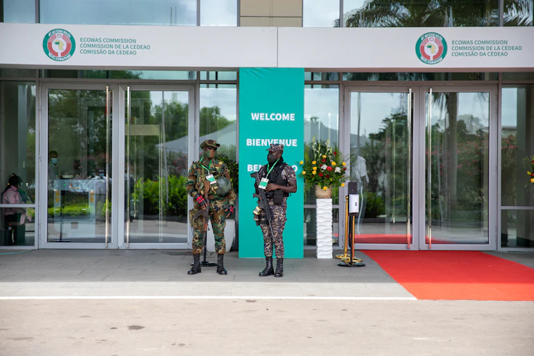 Men in military unifrom holding rifles in front of a building.