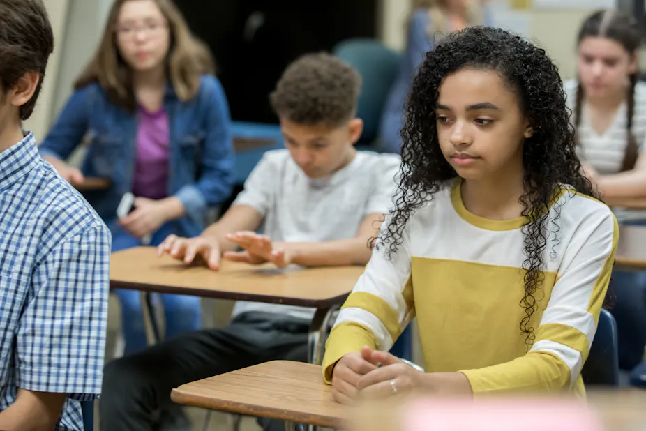 Students sit at their desks in a classroom.