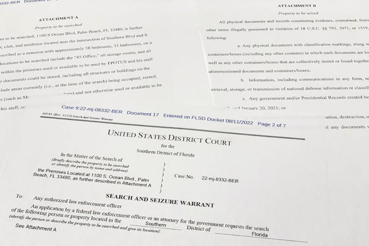 A number of court documents, with the one on top saying prominently 'Search and seizure warrant' in bold type and all capital letters.