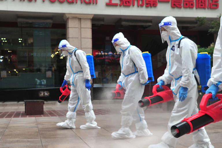 Sanitation workers wearing personal protective equipment spray disinfectant in Shanghai, China.