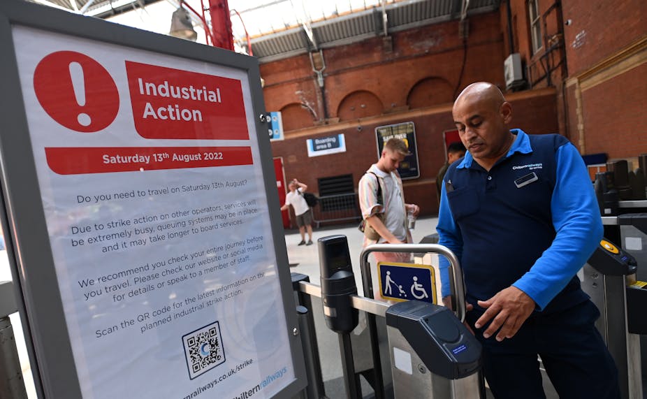 Railway worker by sign alerting train customers of industrial action on August 13 2022.