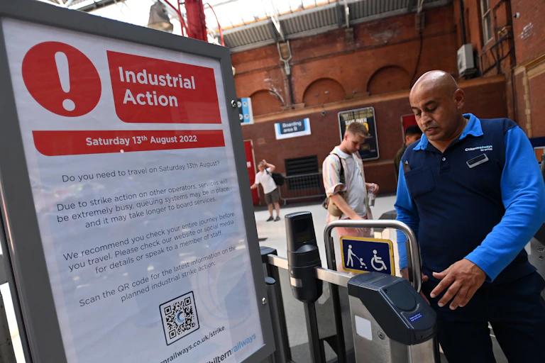 Railway worker by sign alerting train customers of industrial action on August 13 2022.