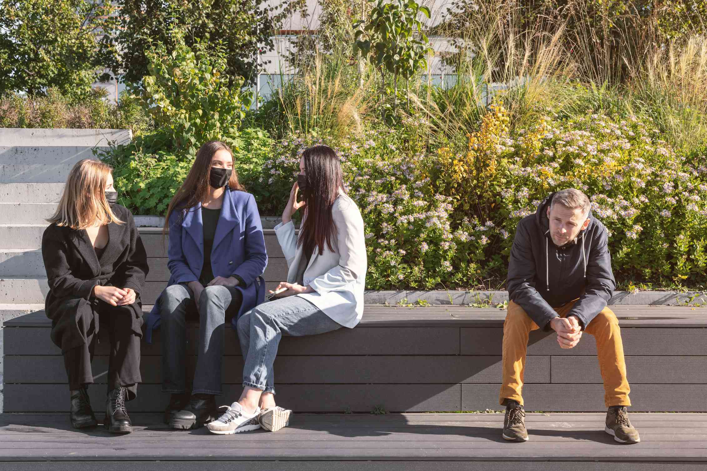 A group of women wearing masks talking, alongside a man not wearing a mask.
