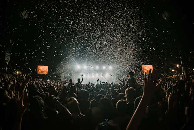 A festival with a big crowd as lights and confetti shower down