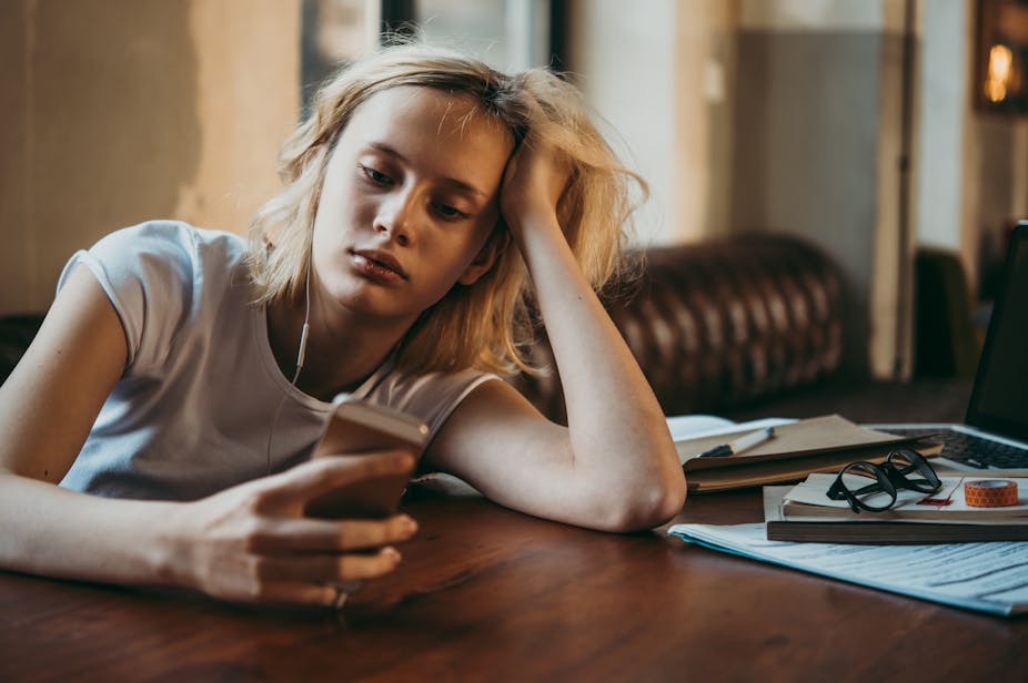 Teenager looks at phone instead of her work