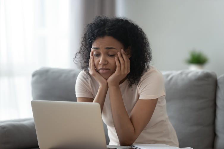 Women stares at laptop with her face in her hands