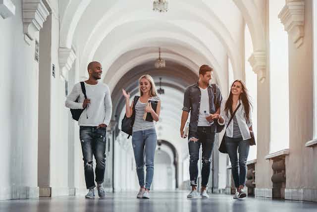 Four young adults walking in hallway