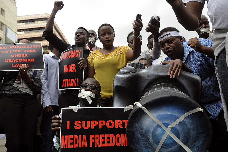 Group of people holding placards calling for media freedom on a street.