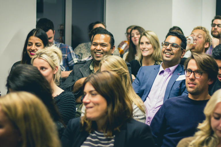 A crowd of people of different ages seen listening and laughing.
