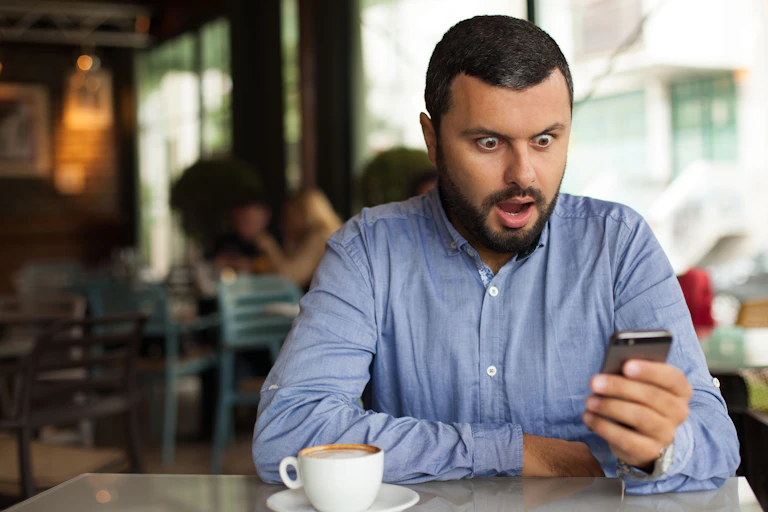 A man is seen gasping in shock at his phone.