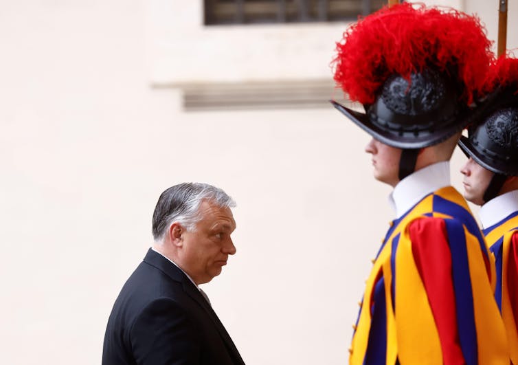 Hungarian prime minister stands in front of a papal guard.