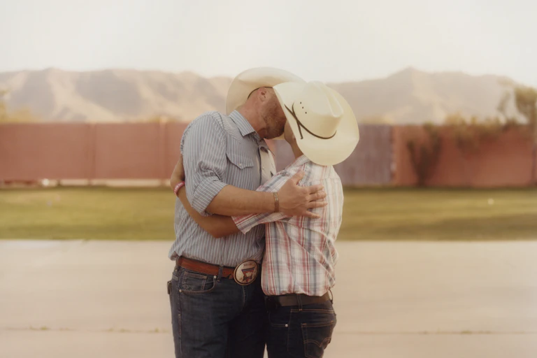Two men in cowboy hats kissing.