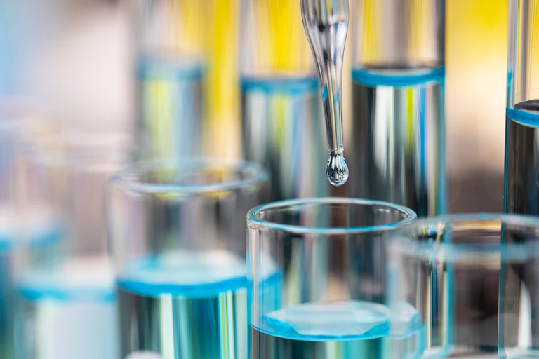 Test tubes in a rack with an eyedropper putting a droplet into one