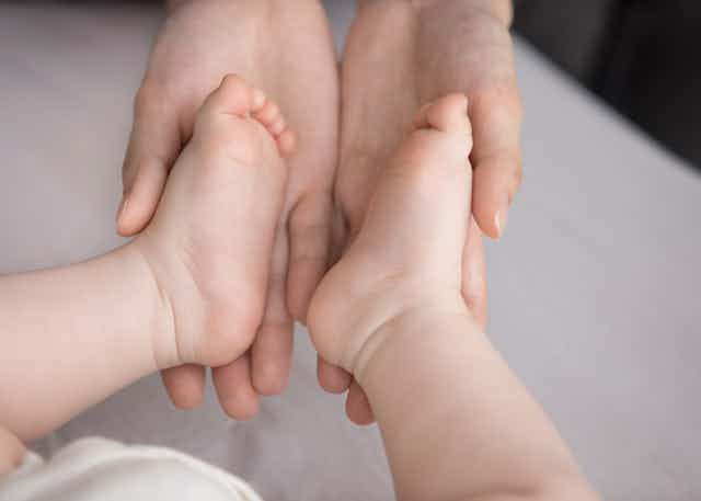 Adult hands cradling an infant's feet
