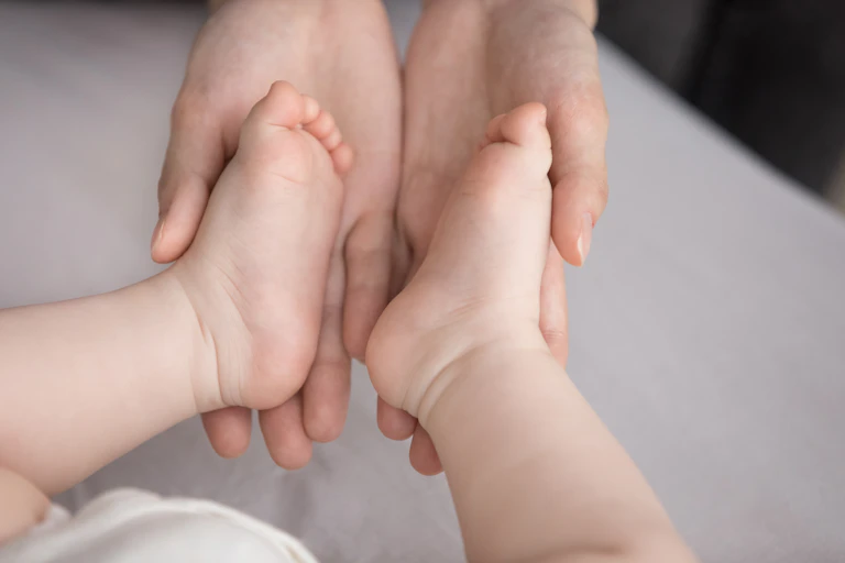 Adult hands cradling an infant's feet