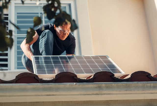 Man putting solar panel on roof