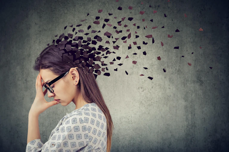 Mujer joven perdiendo partes de la cabeza como símbolo de función mental disminuida.