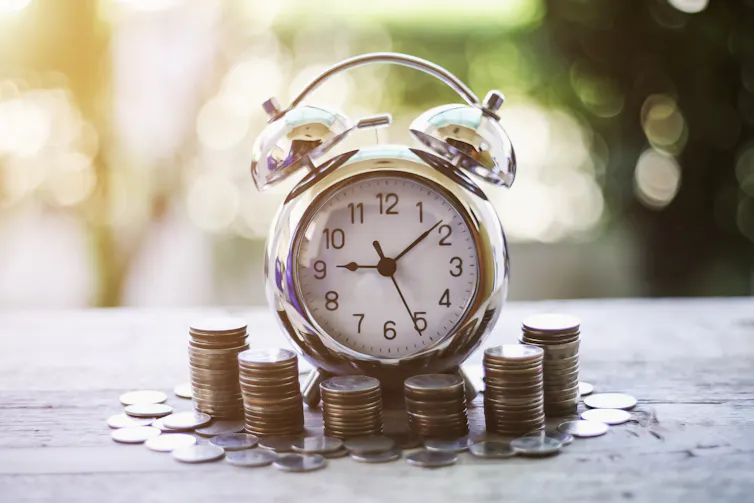Alarm clock surrounded by piles of coins.
