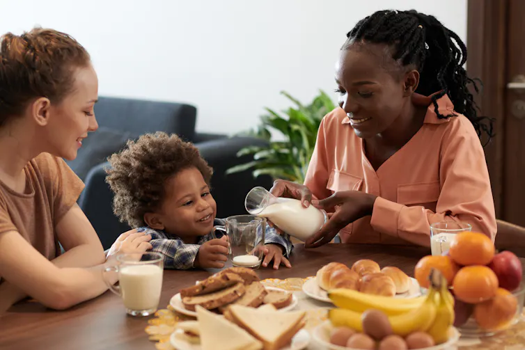 Two moms seen at a table with their little boy.