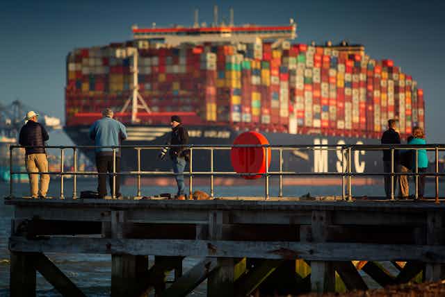 People on a pier in front of a large container ship, Port of Felixstowe, England