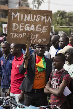 Un homme tient une pancarte durant une manifestation au Mali sur laquelle on peut lire « Minusma dégage »