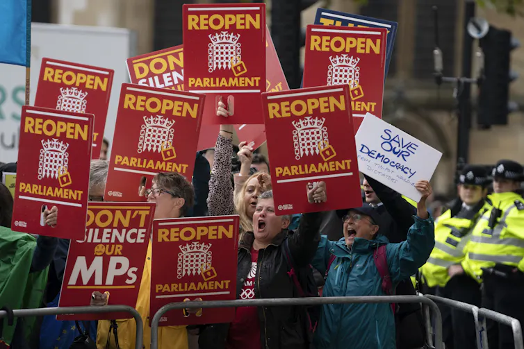 Protestors hold up signs reading 'reopen parliament' and 'don't silence our MPs' at a protest in London in 2019.