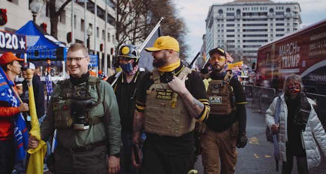 Hombres con banderas y gorras amarillas y negras caminan por la calle.