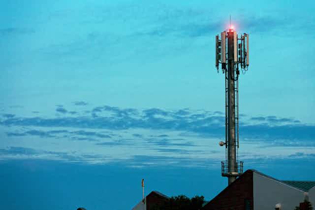 Cell tower with red light set against a sky at twilight.