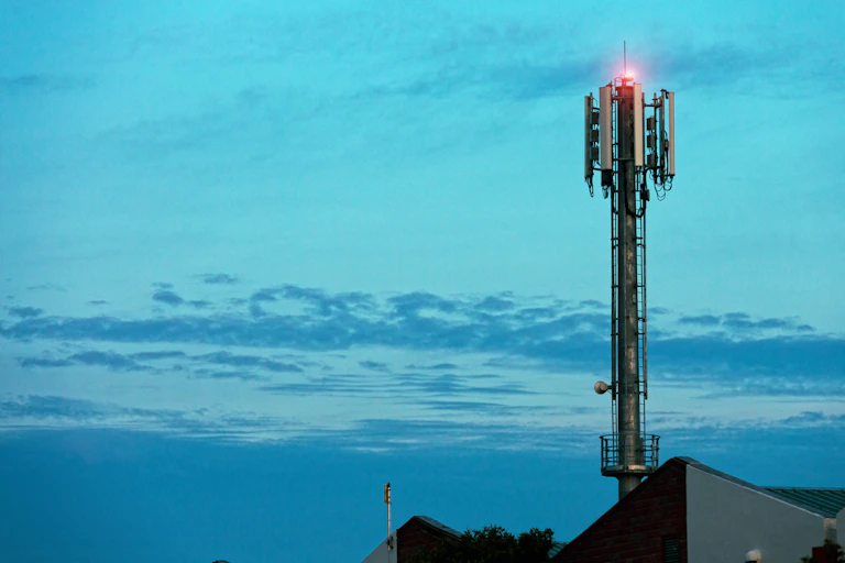 Cell tower with red light set against a sky at twilight.