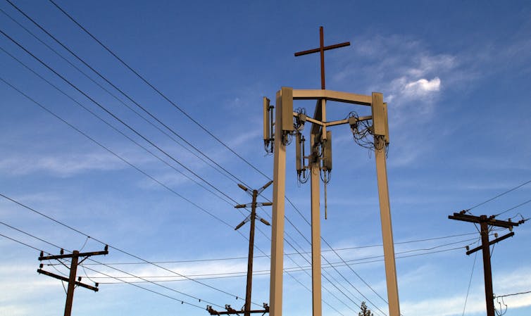 A Christian cross perched atop communication technology.