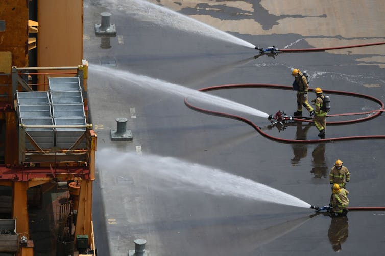 Firefighters working to dampen a fire on a boat.