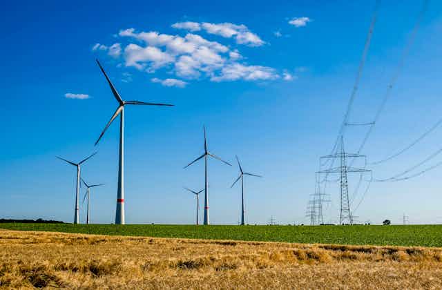 Wind turbines in a farm field with a transmission line running next to them.